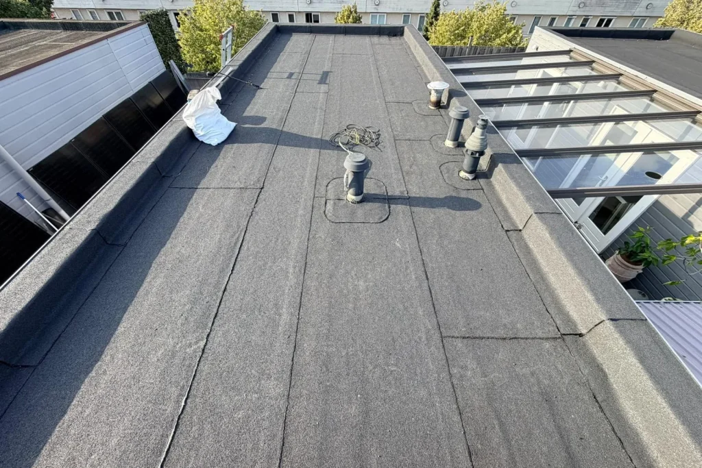 Overlaagd plat dak in Almere Buiten met opnieuw ingewerkte ventilatiepijpen door Maasdamme Dakbeheer